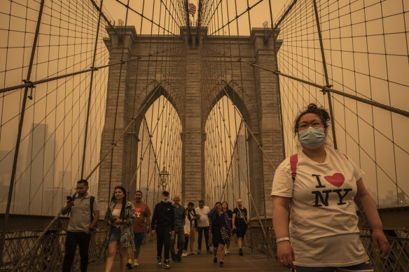 Les gens traversent le pont de Brooklyn au milieu d'une brume dense de fumée de feux de forêt à New York.