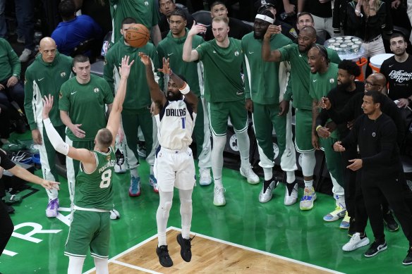 Le gardien de Dallas, Kyrie Irving, tire à trois points sous l'examen minutieux du banc des Celtics et du public local.