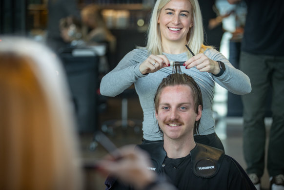 La spécialiste des permanentes Laura Szakaly applique des rouleaux dans les cheveux d'une cliente.