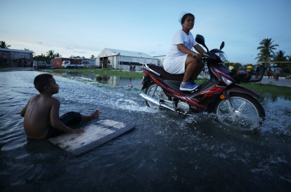 Une femme conduit son scooter dans les eaux de crue à Funafuti, la capitale de Tuvalu, en novembre 2019.