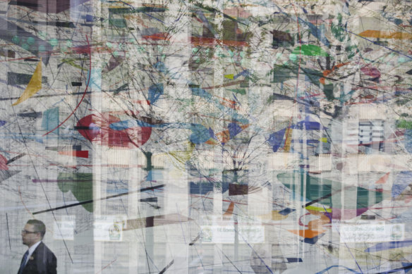 Les gens passent devant la fresque murale de 5 millions de dollars réalisée par Julie Mehretu à l'intérieur du siège de Goldman Sachs.