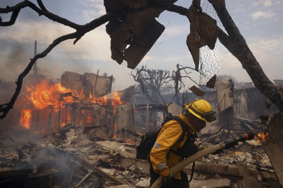 Un pompier combat l'incendie autour d'une structure brûlée dans le quartier Pacific Palisades de Los Angeles en janvier.
