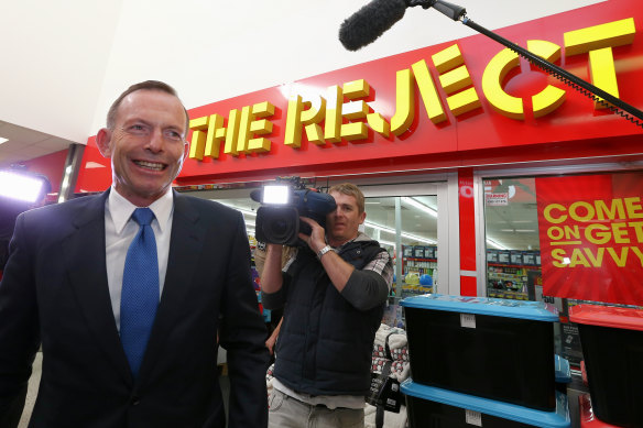 Le Premier ministre Tony Abbott passe devant «The Reject Shop» en 2015.