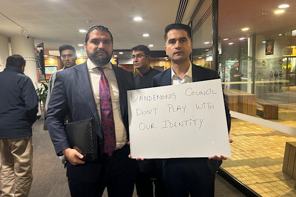 Khalid Amiri tient une plaque de protestation devant la réunion du Dandenong Council aux côtés de Mash Ahmadzai lundi soir.