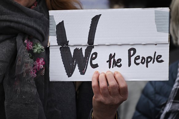 Un démonstrateur tient une bannière lisant «nous le peuple» alors que les gens protestent devant l'ambassade des États-Unis contre le président américain Donald Trump et le conseiller Elon Musk le 5 avril à Berlin, en Allemagne.