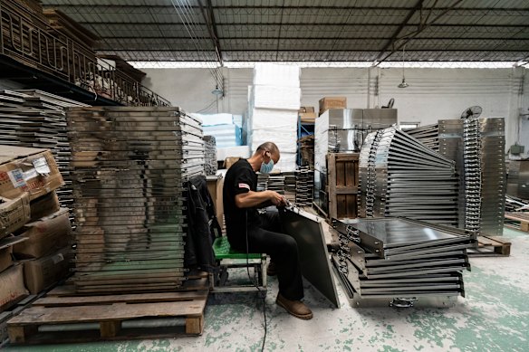 Un travailleur faisant des fours et des ustensiles de cuisine dans une petite usine de Guangzhou. La société prévoit d'acquérir un bras robotique qui utilise l'intelligence artificielle pour reproduire la façon dont une personne soulève les côtés d'un four.