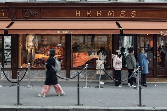 Les acheteurs à l'extérieur de la boutique de vêtements de luxe Hermes International sur Avenue George V dans le centre de Paris, France.