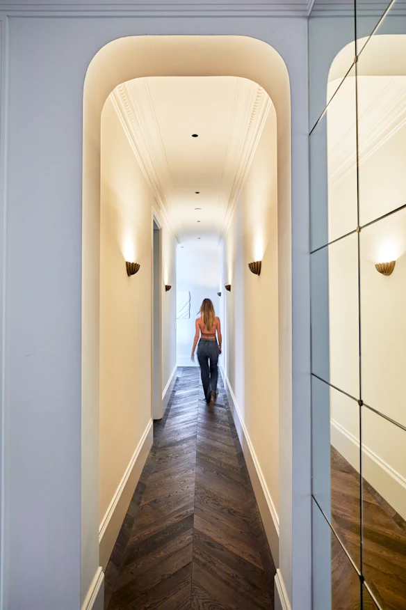 En entrant, le couloir formel, les hauts plafonds, les arcades incurvées et le parquet en chêne créent de la grandeur dans un appartement par ailleurs compact.