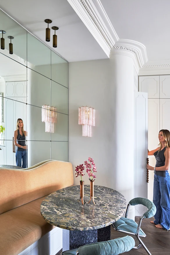 Un mur en miroir ajoute une ambiance sophistiquée à la salle à manger. Il comprend un canapé banquette intégré, une table en marbre, des chaises du milieu du siècle et une applique en verre de Murano.