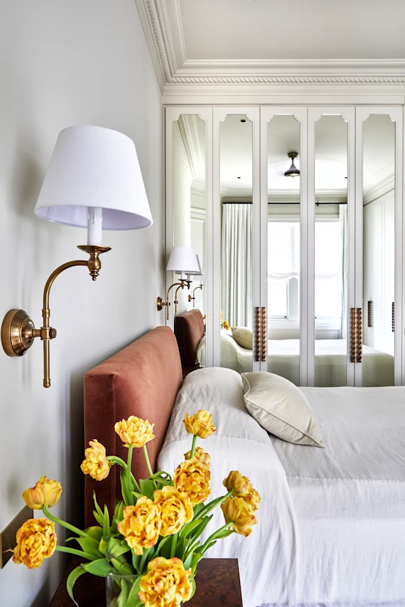 Les armoires en miroir sur mesure offrent du rangement et reflètent la lumière. Les appliques « Soho » sont de chez Florabelle Living, le lit « Burlington » de Coco Republic.