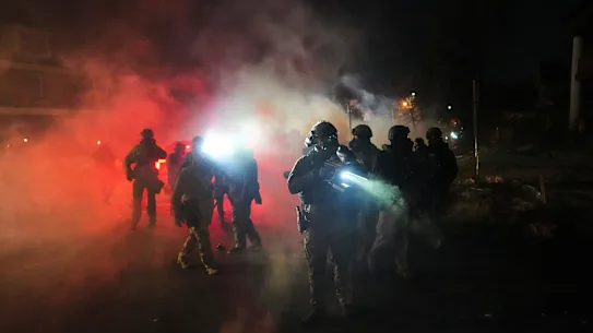 Les forces de l'ordre se tiennent au milieu des gaz lacrymogènes sur les lieux de la fusillade.