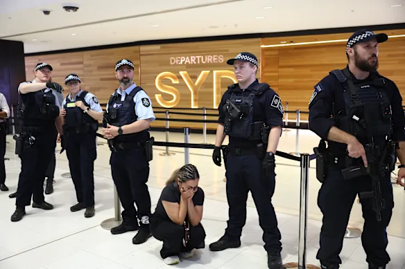 Une supporter de l'équipe féminine iranienne de football est accroupie, en détresse, aux genoux des policiers à l'aéroport international de Sydney.