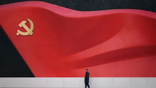 Un homme marche près d’une grande sculpture du drapeau du Parti communiste lors de l’exposition sur l’histoire du Parti communiste chinois à Pékin, en Chine.
