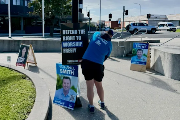 Un membre des Frères portant un t-shirt du Parti libéral installe une affiche lors de la dernière campagne électorale fédérale.