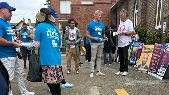 Gareth Hales (au centre, en T-shirt bleu Scott Yung), le fils du leader mondial des Frères, Bruce Hales, au bureau de vote de Bennelong à Sydney le 30 avril.