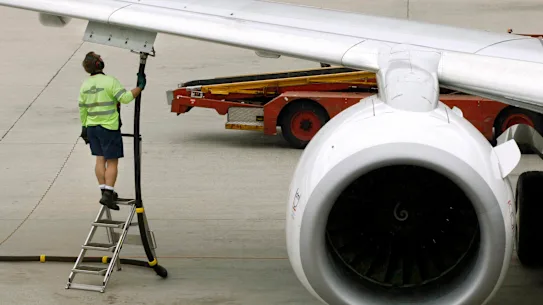Un membre du personnel au sol se tient à côté d'un accessoire de carburant d'un avion Qantas à l'aéroport de Sydney.