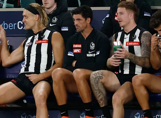 Darcy Moore (à gauche) et Scott Pendlebury (au centre) regardent depuis le banc.