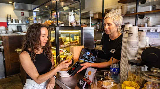Jessica Kotzen, copropriétaire d'Expresso, reçoit le paiement de la cliente Amber Boardman dans son café de Brookvale, Sydney.