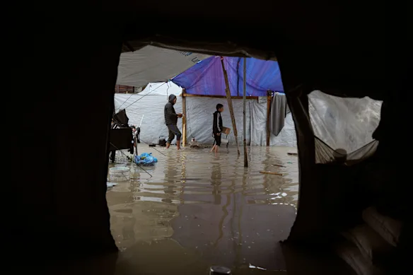Des Palestiniens déplacés traversent un camp de tentes détrempé par la pluie après de fortes pluies fin mars.