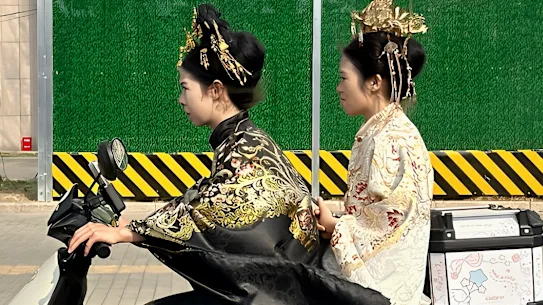 Deux jeunes femmes en costumes traditionnels chinois sur un scooter électrique dans le district de Dongcheng, à l'est de Pékin.