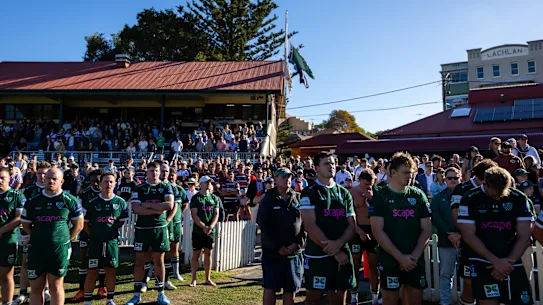   Les gens observent un moment de silence alors que Peter Meagher, victime de la fusillade de masse de Bondi Beach, fait ses adieux à Randwick au Coogee Oval à Coogee avant le match Shute Shield entre Randwick et Eastern Suburbs