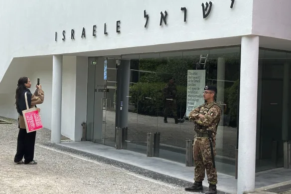 Une femme prend une photo alors qu’un soldat italien patrouille dans le pavillon israélien de la Biennale d’art de Venise en 2024.