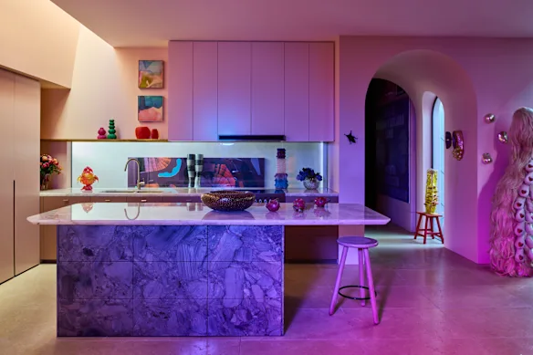 Une cuisine blanche et fade au milieu de tout cet art aurait été décevante. Au lieu de cela, il y a des menuiseries rose saumon foncé et des armoires en cuivre sous le banc de l'îlot central.