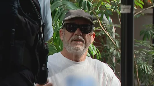 La police à l'extérieur du bâtiment abritant la Commission royale sur l'antisémitisme et la cohésion sociale dans le CBD de Sydney parle à un homme portant un T-shirt antisémite.