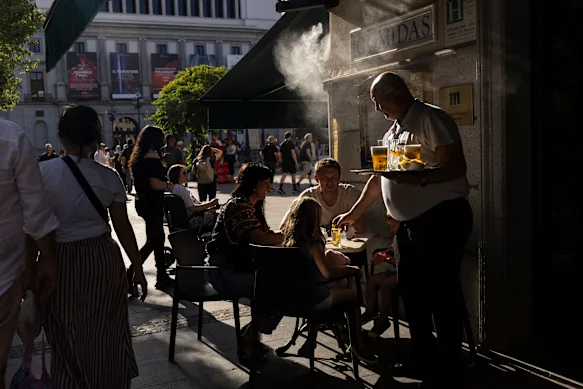 Un serveur travaille dans un bar avec terrasse équipé de pulvérisateurs d'eau à Madrid, en Espagne, pendant la canicule du week-end.