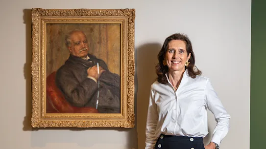 Claire Durand-Ruel photographiée avec un portrait de Paul Durand-Ruel par Auguste Renoir
