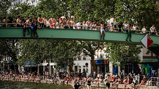 De jeunes Parisiens sautent d'un pont pour se rafraîchir dans le canal Saint-Martin à Paris.