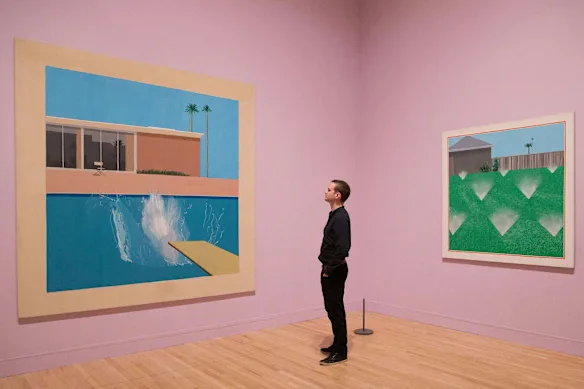 Un spectateur se tient entre A Bigger Splash de Hockney (à gauche) et A Lawn Being Sprinkled.