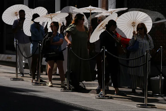 Des personnes munies de parasols font la queue devant un magasin à Londres le 26 juin.