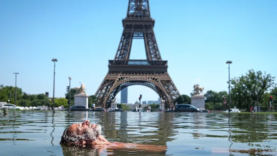 Un homme se rafraîchit dans la fontaine de Varsovie, dans les jardins du Trocadéro, devant la Tour Eiffel à Paris.