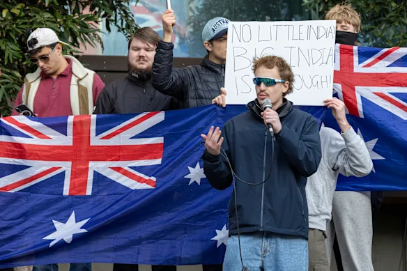 Andre Mamet « Ausmaxx » (au fond à gauche) vérifie son téléphone lors d'un rassemblement anti-Modi auquel ont participé des néo-nazis et leurs associés dirigé par l'influenceur d'extrême droite Mitch Hobbs (au premier plan) en juillet.