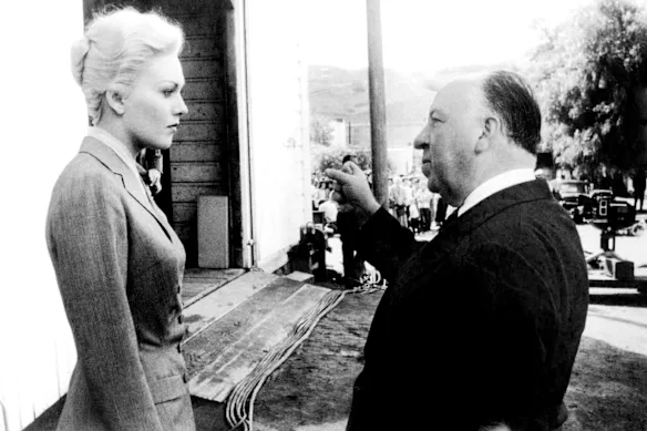 Kim Novak, en costume gris, sur le tournage de Vertigo avec le réalisateur Alfred Hitchcock.