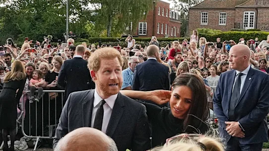 Le prince Harry et Meghan, duchesse de Sussex, rencontrent des gens après avoir assisté aux hommages floraux rendus à feu la reine Elizabeth II devant le château de Windsor, en 2022. 