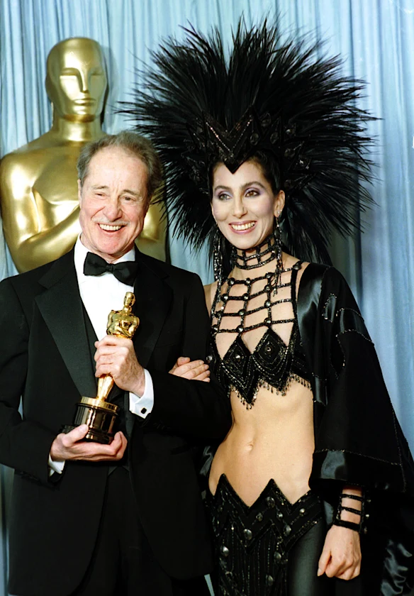 Cher porte une création du designer Bob Mackie alors qu'elle pose avec l'acteur Don Ameche après lui avoir remis l'Oscar du meilleur acteur dans un second rôle en 1986.