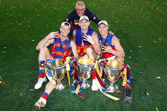 Entraîneur des Lions et co-capitaines (de gauche à droite) Josh Dunkley, Harris Andrews et Hugh McCluggage avec les coupes de premier ministre 2024, 2025 et 2026.