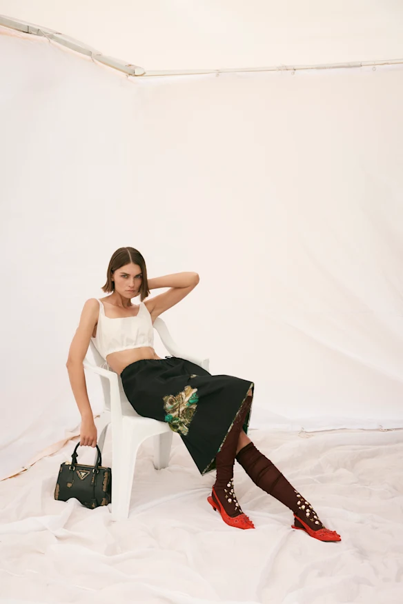 Haut, jupe, chaussettes, chaussures et sac Prada.