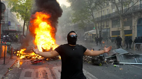Un manifestant fait un geste devant une barricade en feu lors d'une manifestation près de la place de la République.