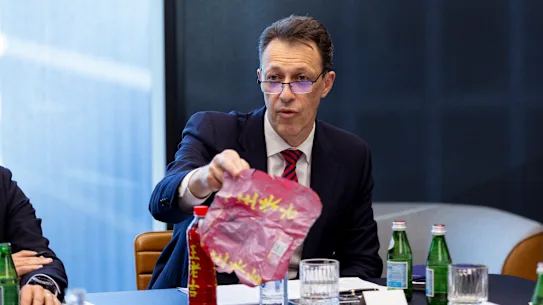 Le chef de Visy, Mark De Wit, montre une bouteille de boisson importée avec un emballage en PVC qui contamine le recyclage du plastique.