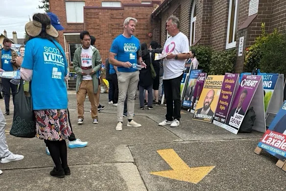 Gareth Hales (au centre, en T-shirt bleu Scott Yung), le fils du leader mondial des Frères, Bruce Hales, dans un isoloir de l'électorat de Bennelong à Sydney en avril.