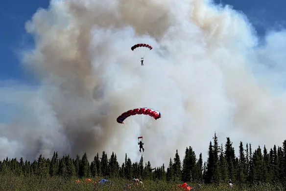 Deux parachutistes fumigènes sautent en parachute dans un incendie de forêt en Alaska en juin.